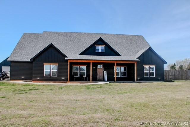 view of front of property with board and batten siding, a front yard, and fence