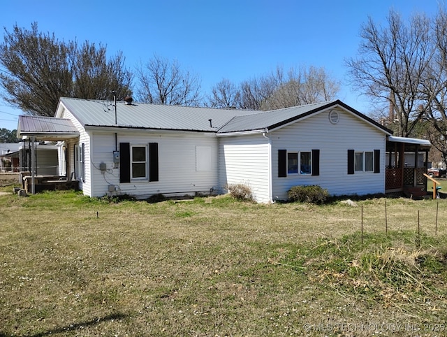 back of property featuring a lawn and metal roof