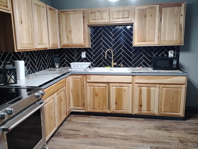 kitchen featuring high end stove, light brown cabinetry, a sink, backsplash, and black microwave