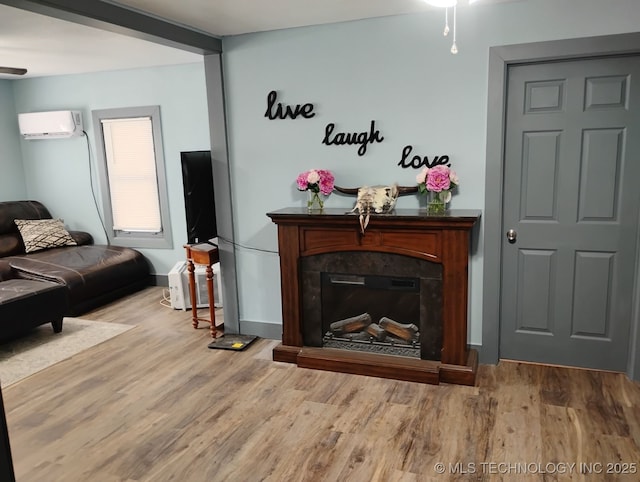 living room featuring ceiling fan, wood finished floors, a fireplace, and a wall mounted AC