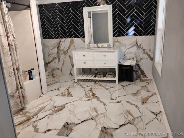 full bath with vanity, stone wall, a shower with curtain, tile walls, and marble finish floor