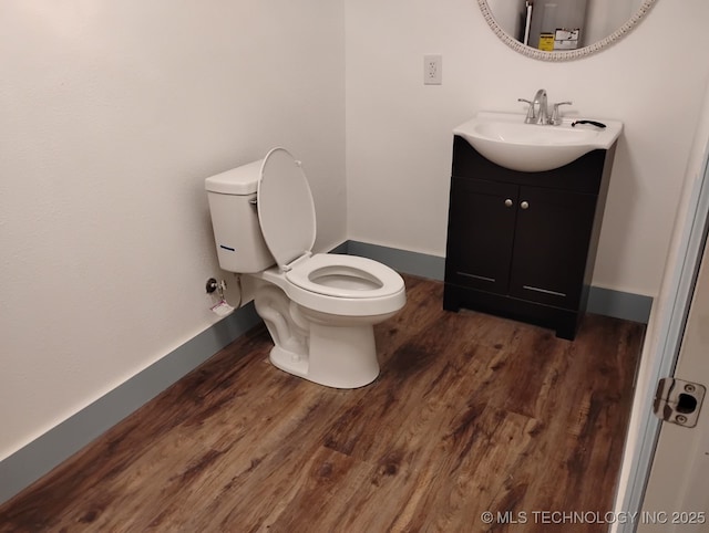 bathroom featuring vanity, wood finished floors, baseboards, water heater, and toilet