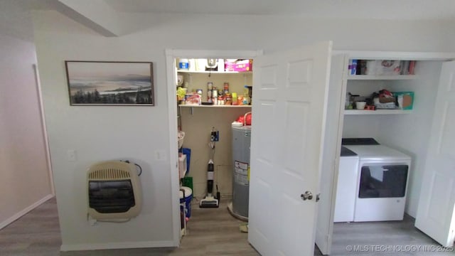 laundry area featuring washing machine and clothes dryer, electric water heater, laundry area, wood finished floors, and heating unit