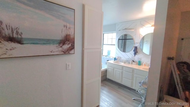 bathroom featuring double vanity, wood finished floors, and a sink