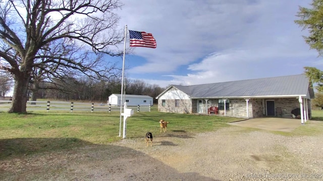 view of front of house with fence, dirt driveway, a front yard, metal roof, and a carport