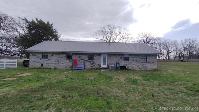 back of house featuring a yard, cooling unit, and metal roof