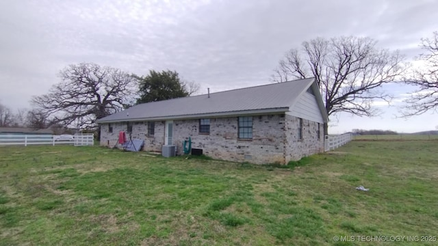 rear view of property with central air condition unit, a yard, fence, and brick siding