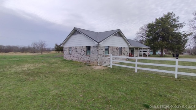 view of side of property featuring a yard, fence, driveway, and metal roof