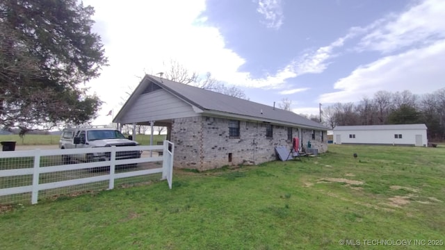 view of home's exterior with a yard, fence, brick siding, and crawl space