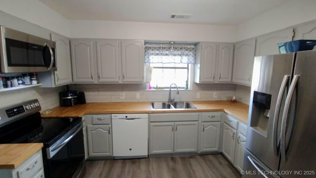 kitchen featuring visible vents, a sink, tasteful backsplash, stainless steel appliances, and butcher block counters