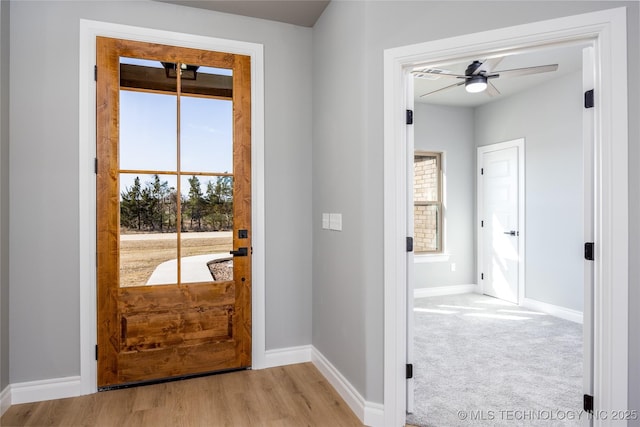 doorway to outside with a ceiling fan, a healthy amount of sunlight, baseboards, and light carpet