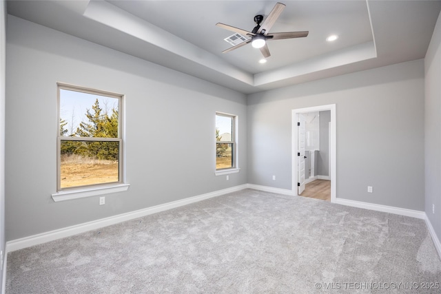 unfurnished bedroom featuring visible vents, baseboards, light colored carpet, recessed lighting, and a raised ceiling