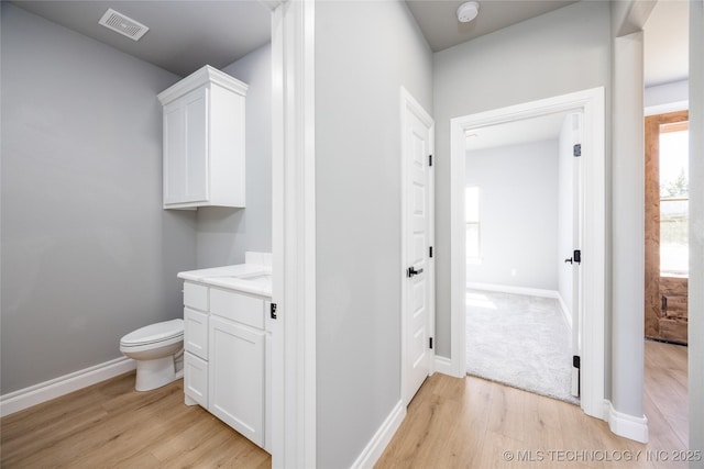 bathroom with vanity, wood finished floors, visible vents, baseboards, and toilet