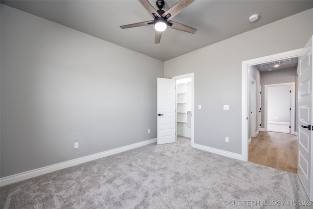 unfurnished bedroom with visible vents, a walk in closet, baseboards, and carpet floors