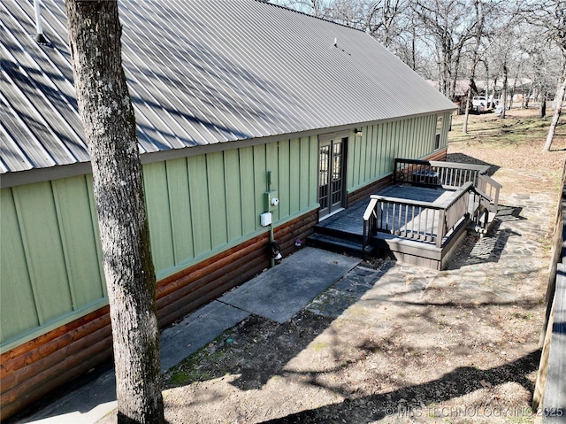 doorway to property featuring a patio area, metal roof, and a deck