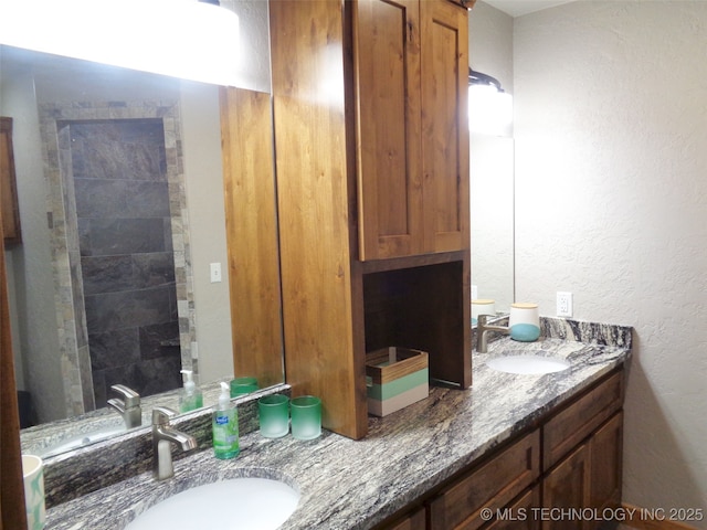 bathroom featuring double vanity, a textured wall, and a sink