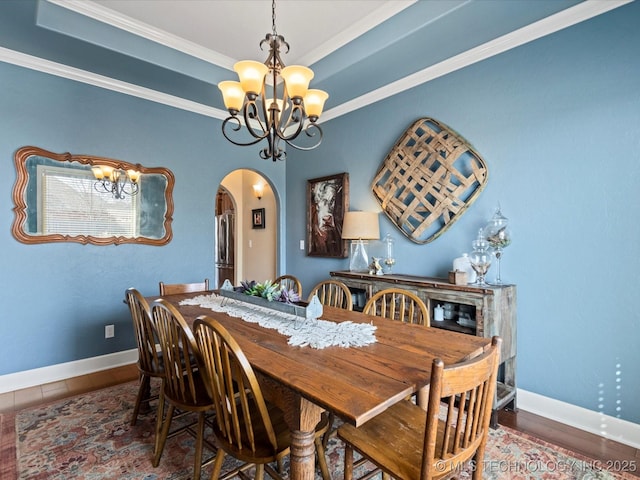 dining area with baseboards, arched walkways, a notable chandelier, and a raised ceiling