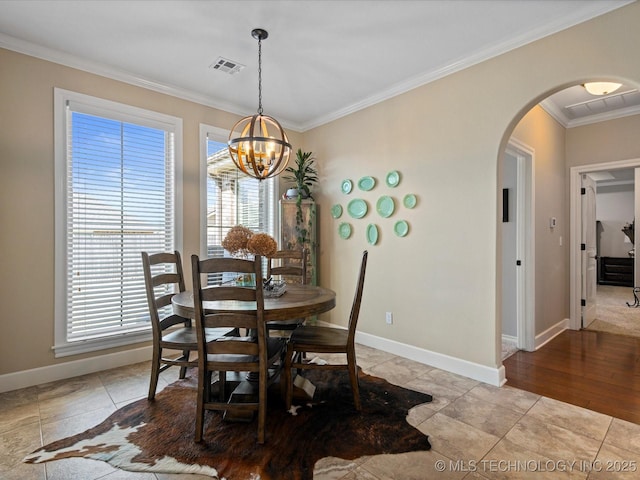 dining area featuring arched walkways, visible vents, crown molding, and a wealth of natural light