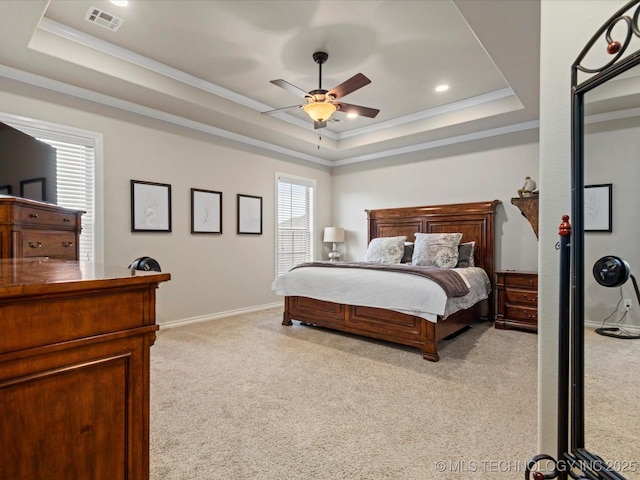 bedroom with a tray ceiling, light carpet, and visible vents