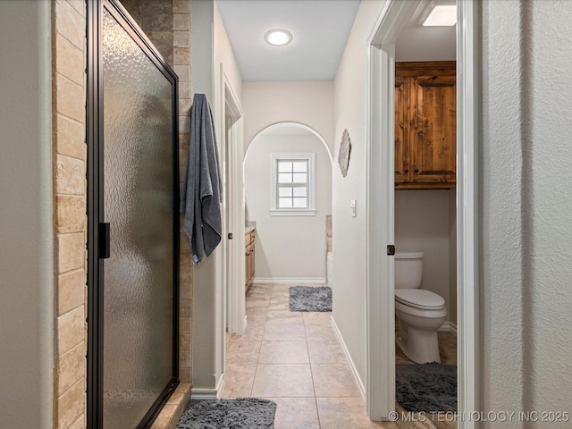 bathroom featuring tile patterned floors, a stall shower, toilet, and baseboards