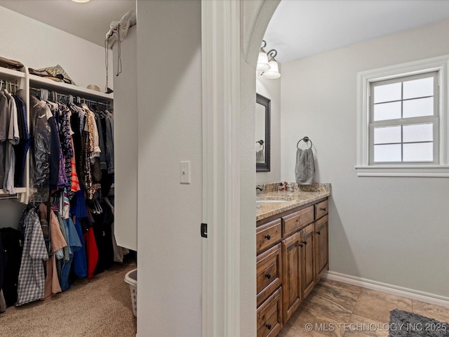 bathroom featuring vanity, a walk in closet, and baseboards