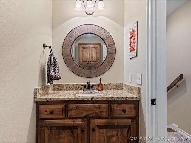 bathroom featuring a notable chandelier, vanity, and baseboards