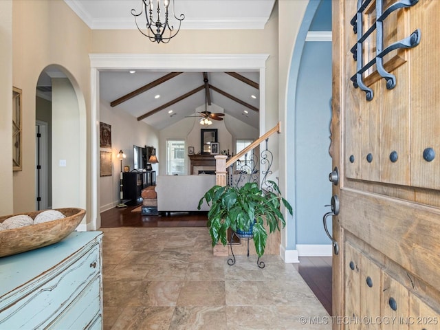 entrance foyer featuring stairway, baseboards, lofted ceiling with beams, arched walkways, and ceiling fan