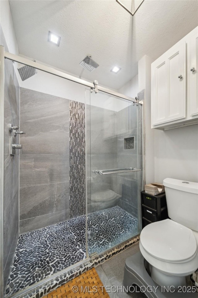 bathroom featuring a stall shower, toilet, and a textured ceiling