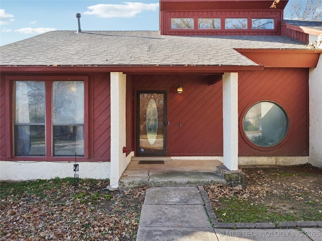 entrance to property with stucco siding and a shingled roof