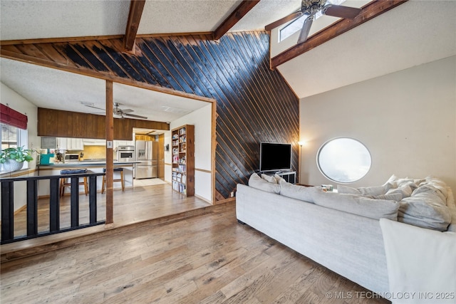 living room with beamed ceiling, wood finished floors, and a ceiling fan