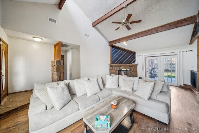 living area with beam ceiling, wood finished floors, a ceiling fan, and a textured ceiling