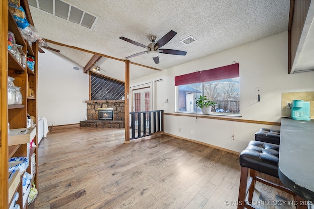 unfurnished living room featuring visible vents, wood-type flooring, a textured ceiling, and ceiling fan