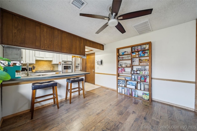 kitchen with visible vents, backsplash, ceiling fan, light wood-style flooring, and appliances with stainless steel finishes