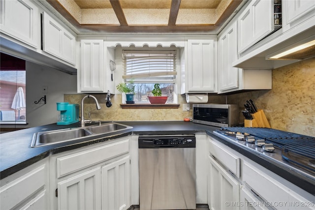 kitchen featuring a sink, under cabinet range hood, dark countertops, appliances with stainless steel finishes, and white cabinets