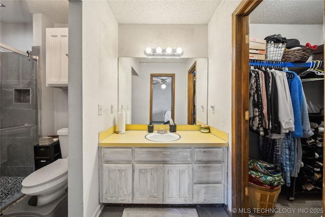 bathroom featuring toilet, a textured ceiling, a shower stall, a spacious closet, and vanity