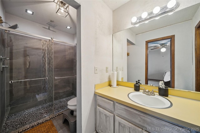 bathroom featuring ceiling fan, toilet, a stall shower, and vanity