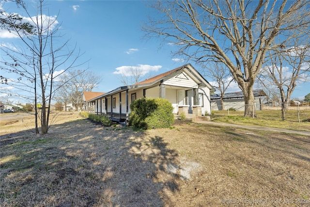 view of side of property featuring a lawn, a porch, and fence