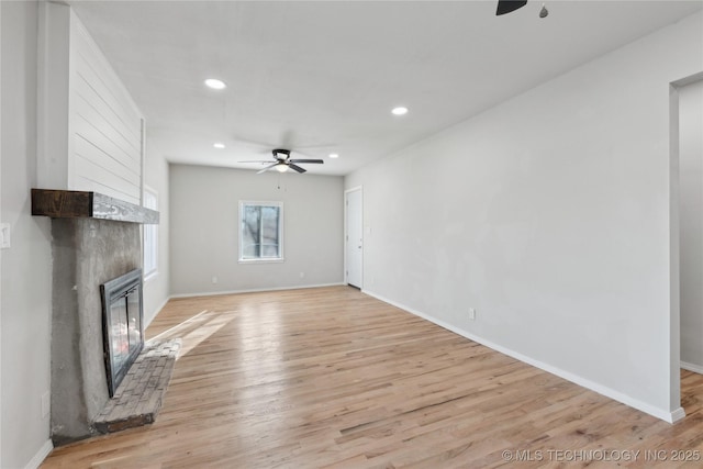 unfurnished living room featuring recessed lighting, a large fireplace, ceiling fan, and light wood finished floors