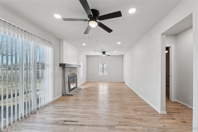 unfurnished living room featuring a glass covered fireplace, recessed lighting, light wood-type flooring, and a ceiling fan