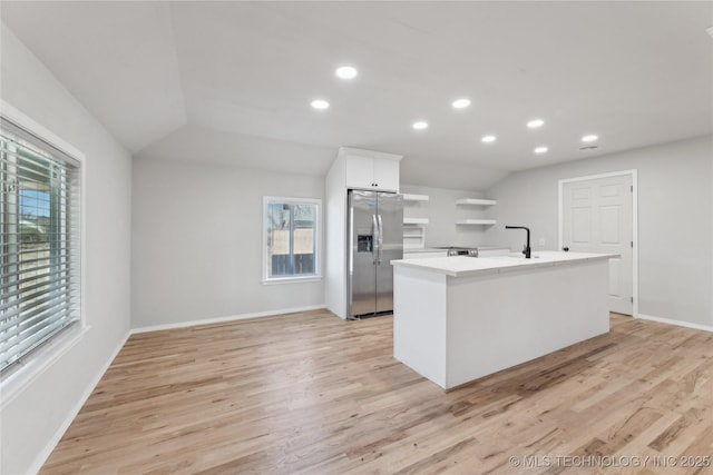 kitchen with white cabinetry, light wood-style floors, stainless steel refrigerator with ice dispenser, and a wealth of natural light