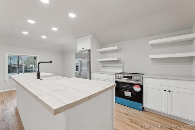 kitchen with a center island with sink, light wood finished floors, open shelves, a sink, and appliances with stainless steel finishes