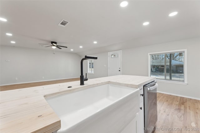 kitchen featuring visible vents, a ceiling fan, a sink, stainless steel dishwasher, and light wood finished floors