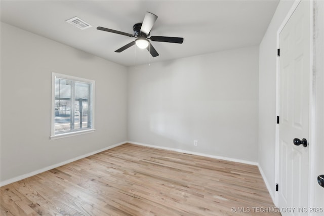 spare room with wood finished floors, a ceiling fan, visible vents, and baseboards