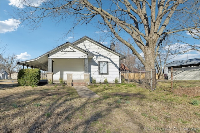 bungalow featuring a carport, a chimney, a front lawn, and fence