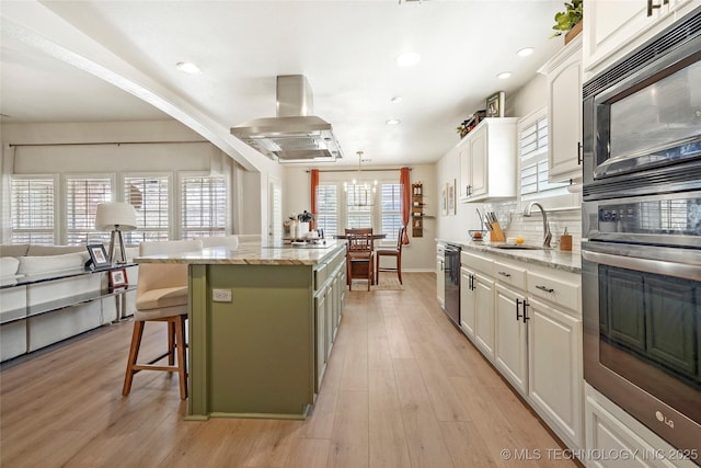 kitchen featuring island exhaust hood, a sink, stainless steel appliances, tasteful backsplash, and a center island