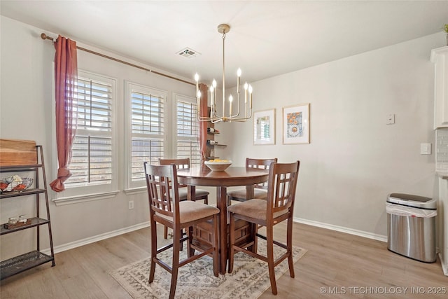 dining area featuring light wood finished floors, visible vents, baseboards, and an inviting chandelier