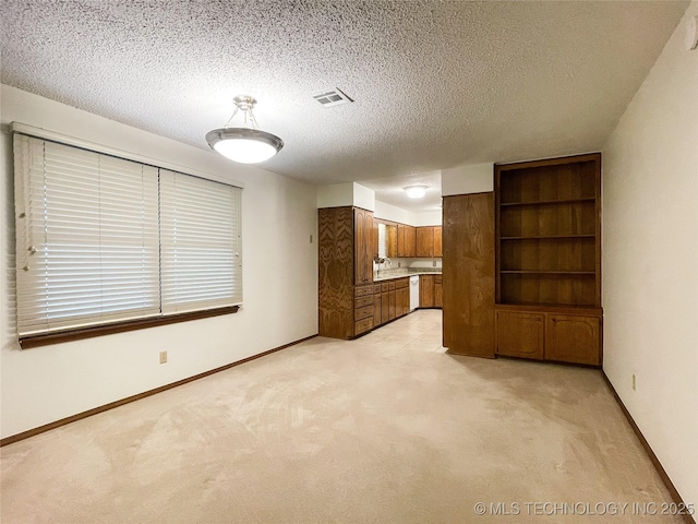 unfurnished living room with visible vents, baseboards, light colored carpet, and a textured ceiling