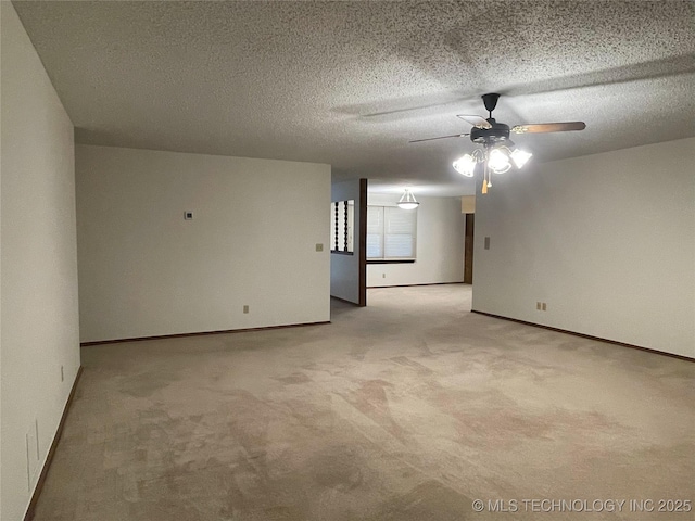 carpeted spare room featuring a textured ceiling, baseboards, and ceiling fan