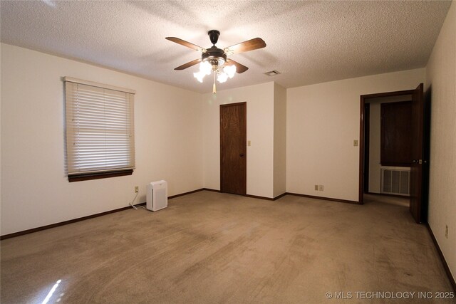 spare room featuring visible vents, light carpet, a textured ceiling, and a ceiling fan