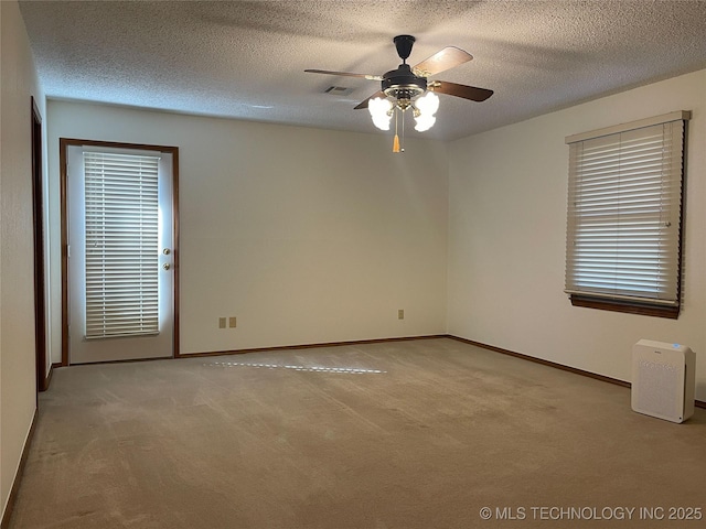 carpeted spare room with visible vents, a textured ceiling, baseboards, and a ceiling fan